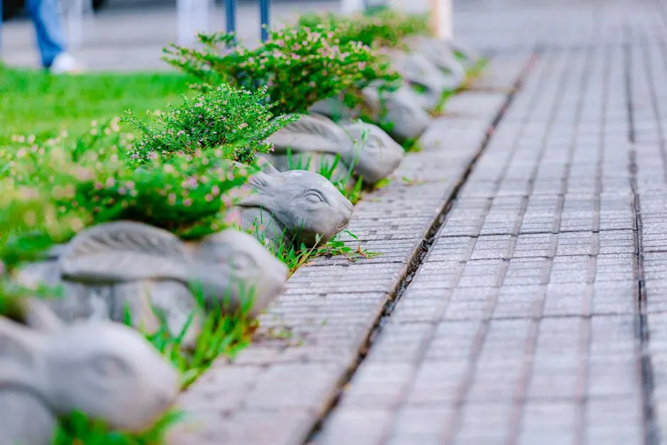 A row of rabbit statues adorns a garden pathway, bordered by lush green plants.