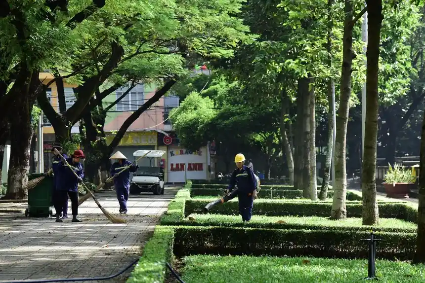 City park maintenance workers tending to greenery on a sunny day, creating a clean and serene environment.